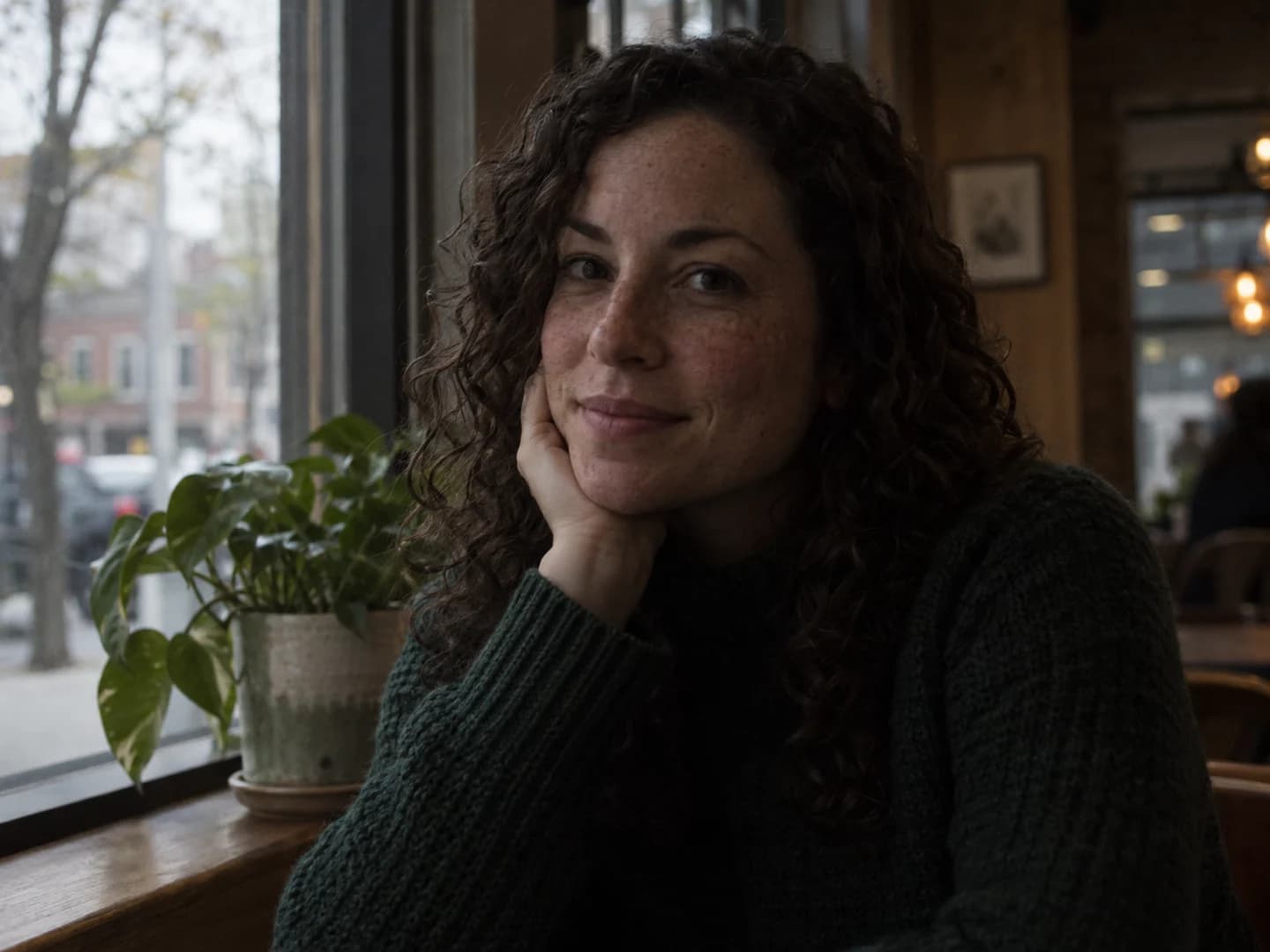 Underexposed cafe portrait of a woman in a green sweater