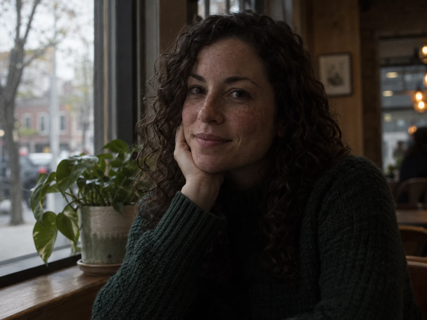 Underexposed cafe portrait of a woman in a green sweater